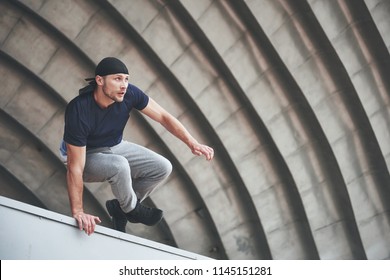 Young Man Doing Parkour Jump In Urban Space In The City Sunny Spring Summer Day