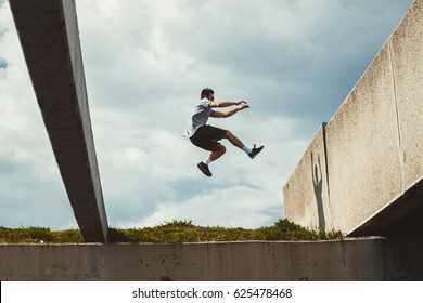 Young Man Doing Parkour Jump  In Urban Space In The City  Sunny Spring Summer Day 
