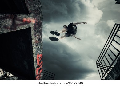 Young Man Doing Parkour Jump In The City Shot 
From Below