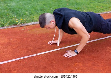 Young man doing push ups in the morning outdoor on the running race track