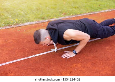 Young man doing push ups in the morning outdoor on the running race track