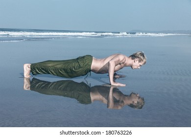 Young man doing push ups during fitness training on sea beach