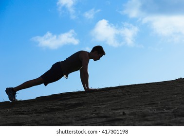 Young man doing push ups outdoors. 