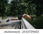 Young man doing push-ups on a bridge in a park. Dedicated fitness enthusiast exercising in an outdoor setting. Physically fit and determined.