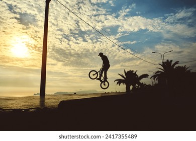 Young man doing ramp jump stunt on bmx bicycle on sunset. Silhouette unrecognizable of a guy with a bmx bicycle. BMX rider. - Powered by Shutterstock