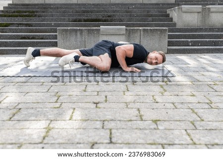 Young man doing a spider push-up or side kick push-up outdoor on concrete background in the city