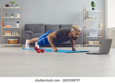 Young Man Doing Sports Workout Online And Looking At Video On Laptop On Fitness Carpet At Home. Online Fitness Training From Home Concept