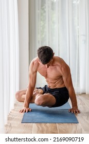 Young Man Doing Strength Pilates Or Yoga Workout In The Morning. Muscular Man Practicing Sweat Yoga At Home