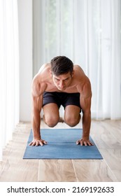 Young Man Doing Strength Pilates Or Yoga Workout In The Morning. Muscular Man Practicing Sweat Yoga At Home