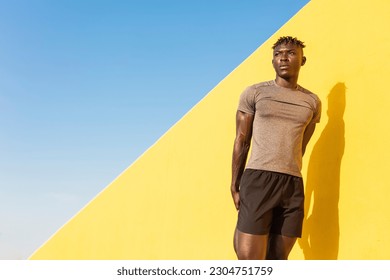 Young man doing stretching exercise outside. African man training at the beach.