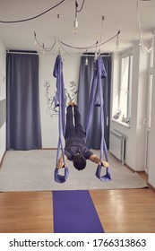 Young Man Doing Superman Pose While Practicing Antigravity Yoga In Studio