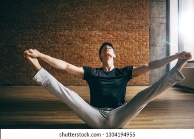 Young Man Doing Yoga In Big Bright Training Gym