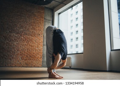 Young Man Doing Yoga In Big Bright Training Gym