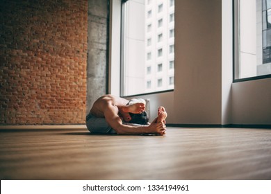 Young Man Doing Yoga In Big Bright Training Gym