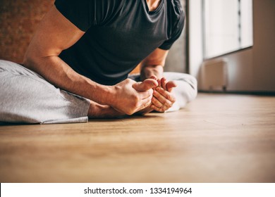 Young Man Doing Yoga In Big Bright Training Gym