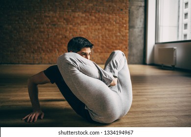 Young Man Doing Yoga In Big Bright Training Gym