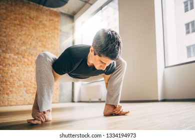 Young Man Doing Yoga In Big Bright Training Gym