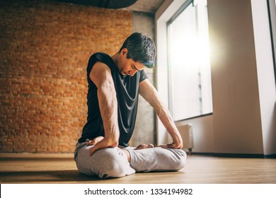 Young Man Doing Yoga In Big Bright Training Gym