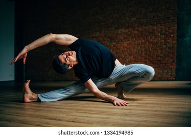 Young Man Doing Yoga In Big Bright Training Gym