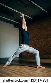 Young Man Doing Yoga In Big Bright Training Gym