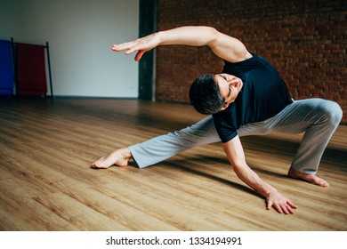 Young Man Doing Yoga In Big Bright Training Gym