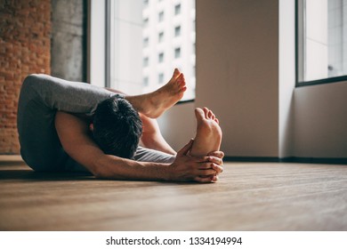 Young Man Doing Yoga In Big Bright Training Gym