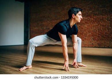 Young Man Doing Yoga In Big Bright Training Gym