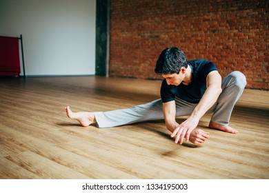 Young Man Doing Yoga In Big Bright Training Gym