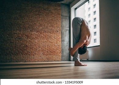 Young Man Doing Yoga In Big Bright Training Gym