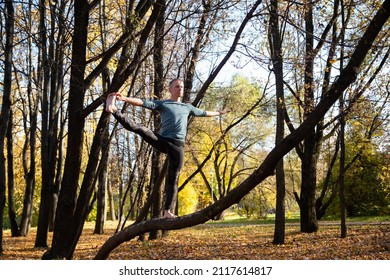 Young man doing yoga exercise in autumn park on yellow foliage - Shutterstock ID 2117614817