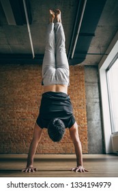 Young Man Doing Yoga Handstand In Big Bright Training Gym