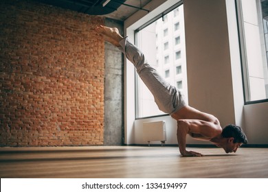 Young Man Doing Yoga Handstand In Big Bright Training Gym