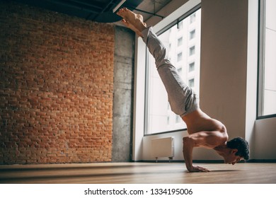 Young Man Doing Yoga Handstand In Big Bright Training Gym