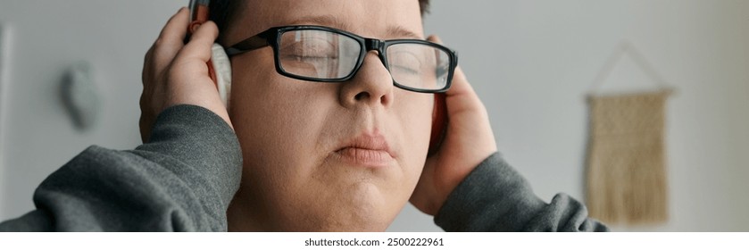 A young man with Down syndrome listens intently to music while relaxing at home. - Powered by Shutterstock