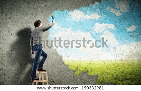 Young man drawing a cloudy blue sky on the wall