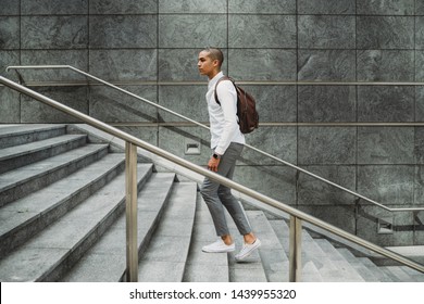 Young Man Dressed In Casual Clothes And Backpack In The City Center Is Going Up The Stairs - Millennial Is Going To Work