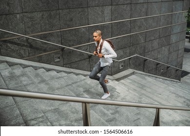 Young Man Dressed In Casual Clothes And Backpack In The City Center Is Going Up The Stairs - Millennial Is Going To Work