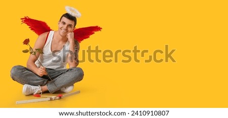 Young man dressed as Cupid with rose on yellow background with space for text. Valentine's Day celebration