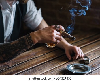 A young man dressed in a vintage style smokes a cigar in a pub, close-up, Selective focus - Powered by Shutterstock