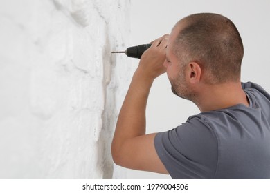 Young Man Drilling Hole In Wall 