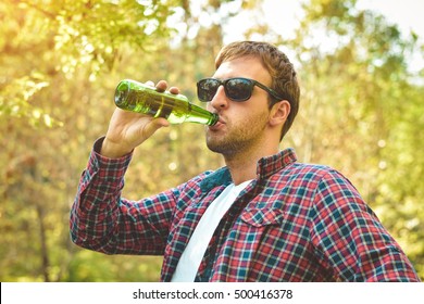 young man drinking beer from bottle outdoors - Powered by Shutterstock