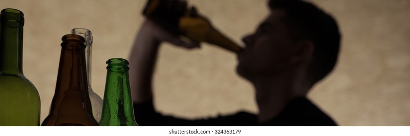 Young man drinking beer during party at home