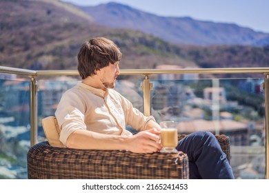 Young man drinking coffee on the balcony, standing behind a mountain - Powered by Shutterstock