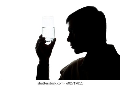 Young man drinking a glass of sparkling water, checks the quality - silhouette