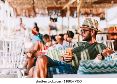 Young man drinking ice coffee in a beach bar