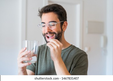 Young Man Drinking Medicine At Home