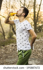 Young Man Drinking Orange Juice In Nature