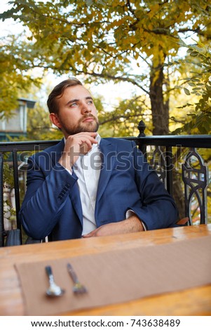 Young man drinking tea with sweets on a blurred natural background.