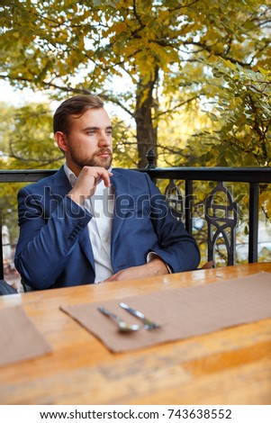 Young man drinking tea with sweets on a blurred natural background.