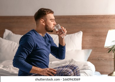 Young Man Drinking Water In Bedroom At Night